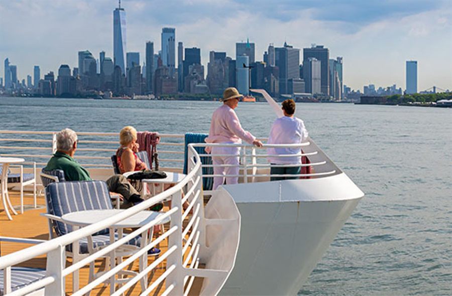 Guests on the bow of a small cruise ship looking at the Manhattan skyline from the Hudson